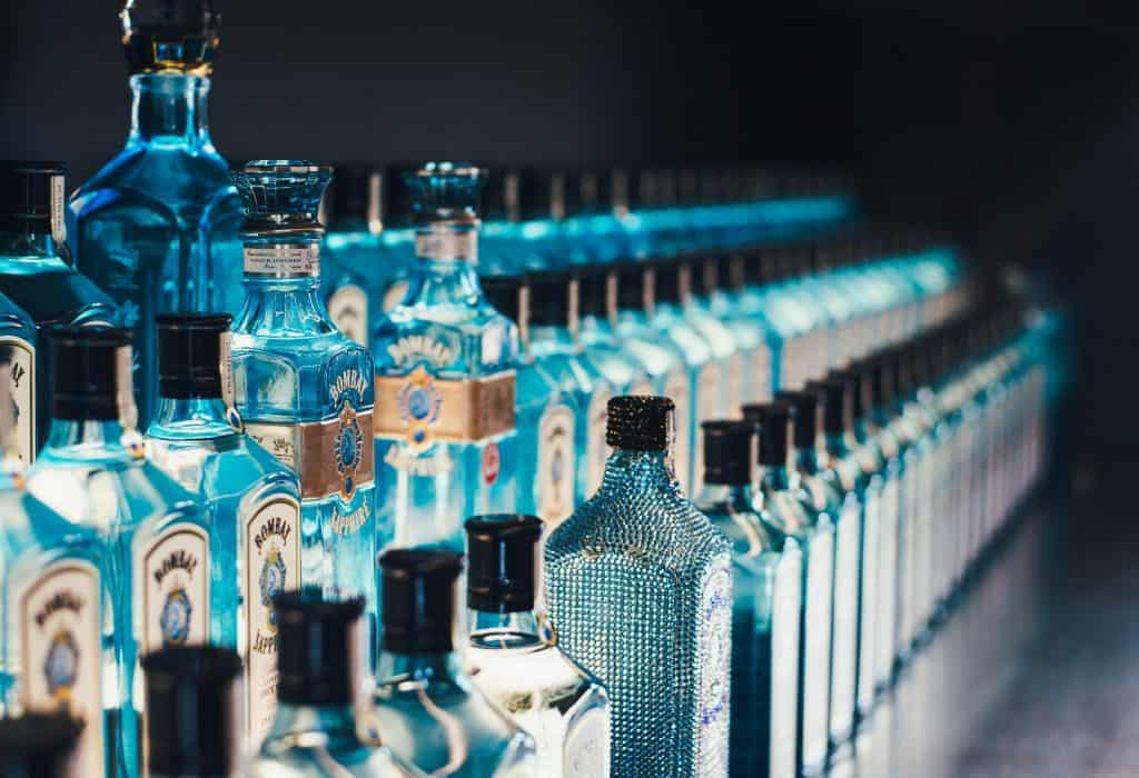 Several rows of bottles of Bombay Sapphire gin on a dark background.