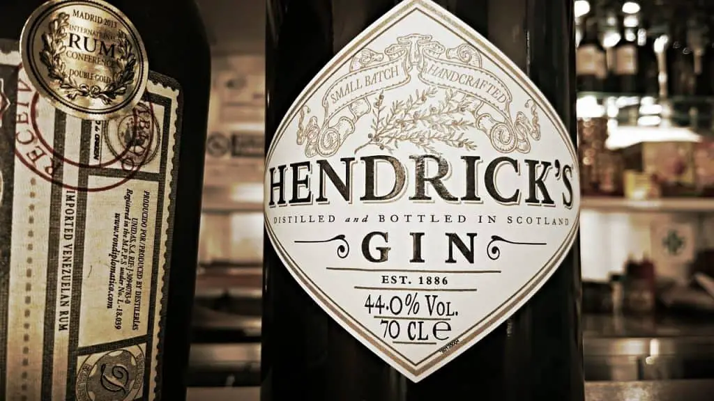 Up close view of a beautiful Hendrick's Gin bottle. A dark black bottle with an off-white label displaying the brands logo.