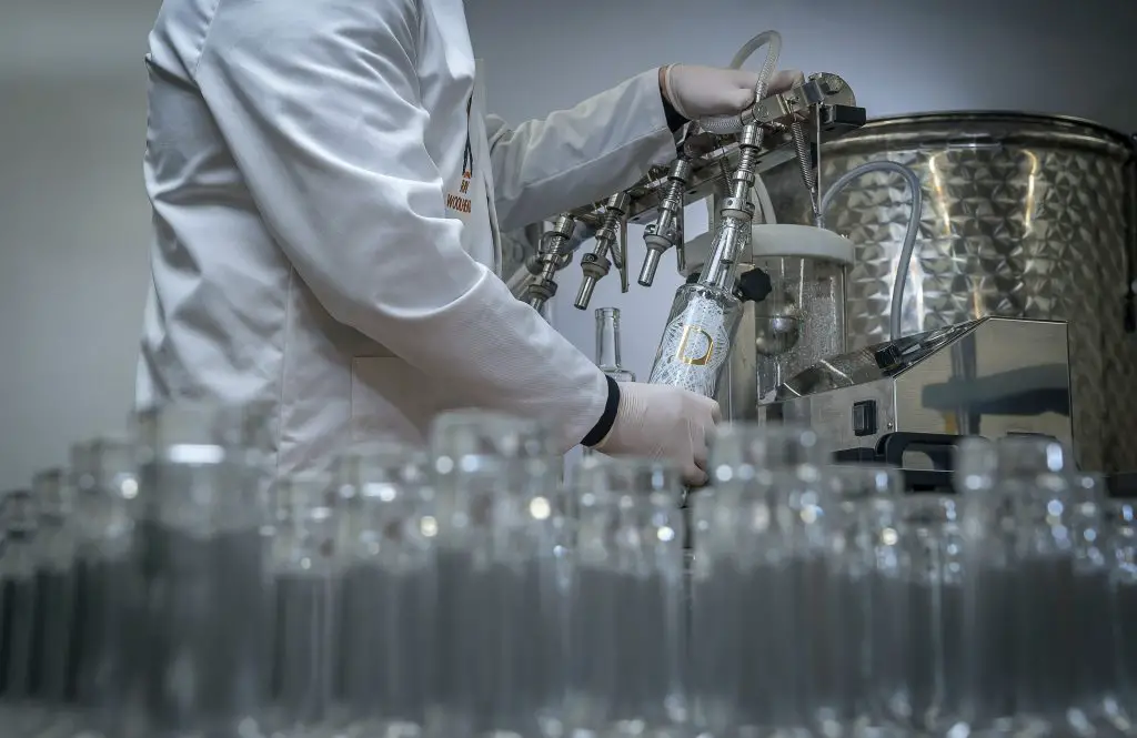 A man rinsing out glass bottles using an industrial machine.