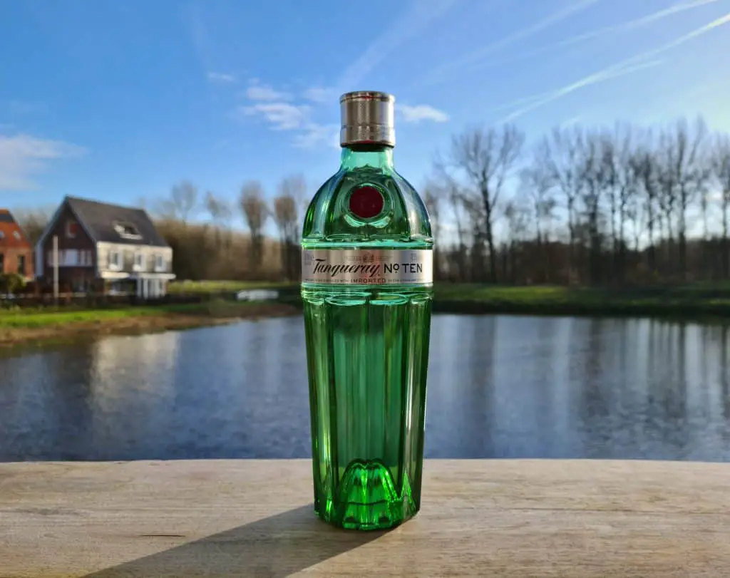 A beautiful green bottle of Tanqueray number ten gin on a wooden table.