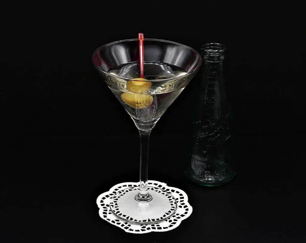 A gin martini on a martini glass on a black background.