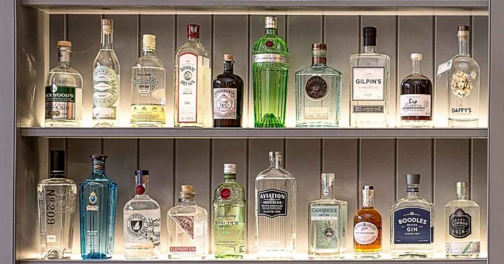 A collection of opened and unopened bottles of gin of different brands and flavors.
